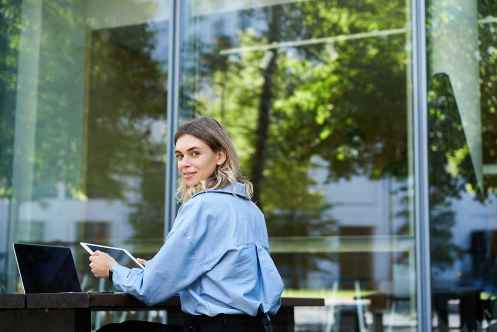 Donna che lavora con un tablet seduta nello spazio esterno di un'azienda